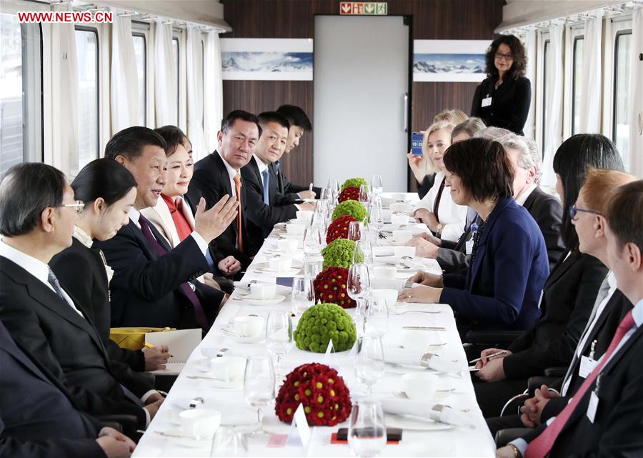 O presidente chinês Xi Jinping e a sua esposa, Peng Liyuan, desfrutam de um chá, enquanto dialogam com a presidente suíça Doris Leuthard e o seu marido, Roland Hausin, num trem especial do governo, que liga Zurique a Berna, capital da Suíça.