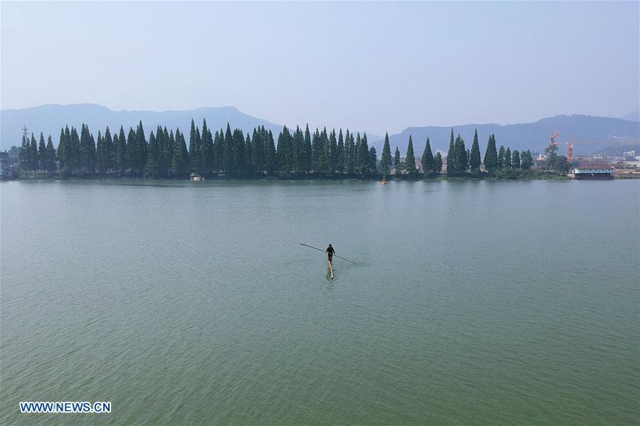 Cidadão de Hangzhou atravessa rio Xin'an com duas canas de bambu