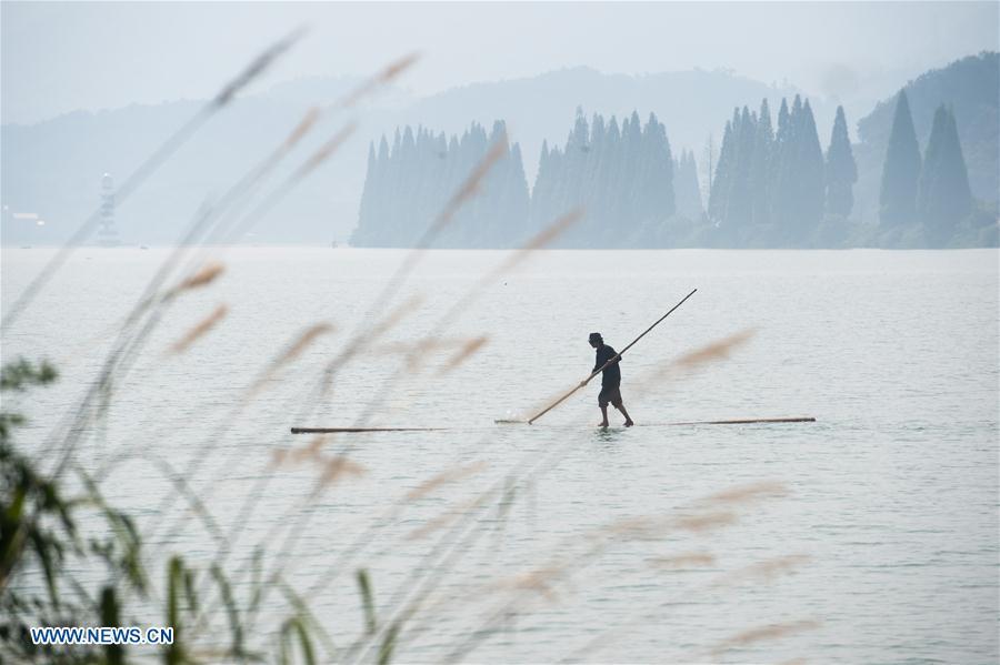 Cidadão de Hangzhou atravessa rio Xin'an com duas canas de bambu