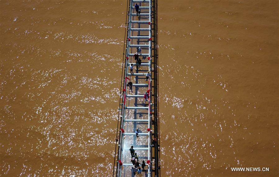 Turistas caminham em ponte de vidro sobre o rio Amarelo