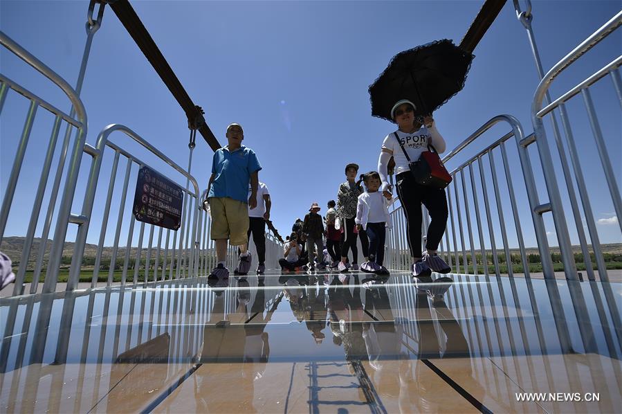 Turistas caminham em ponte de vidro sobre o rio Amarelo