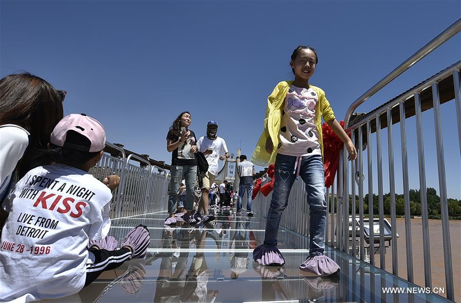 Turistas caminham em ponte de vidro sobre o rio Amarelo