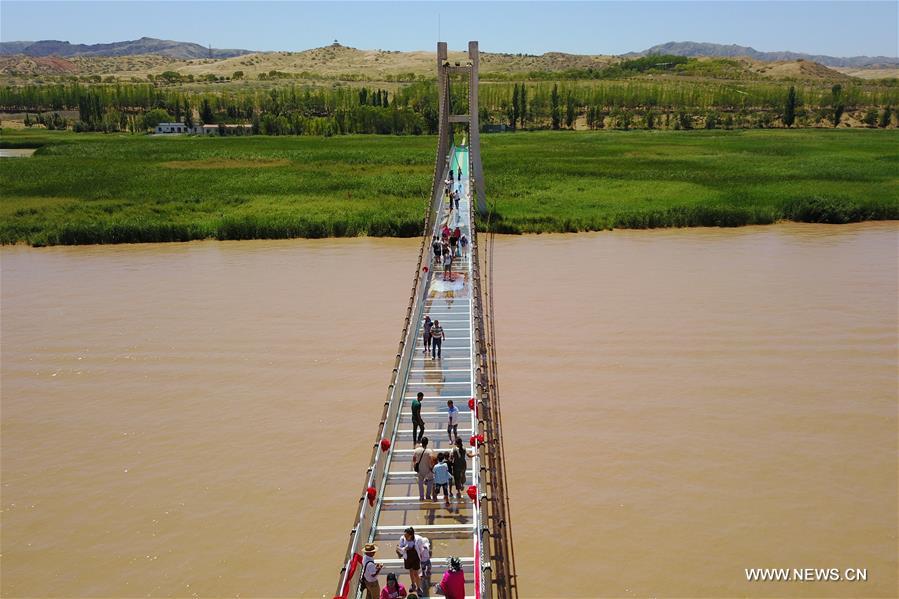 Turistas caminham em ponte de vidro sobre o rio Amarelo