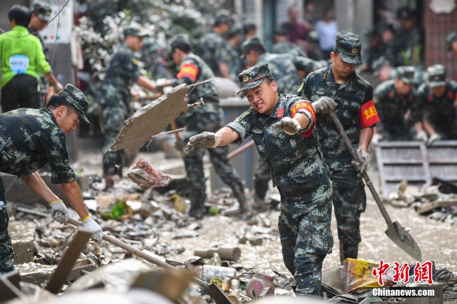 Oficiais e soldados limpam lama depois da inundação em Chongqing