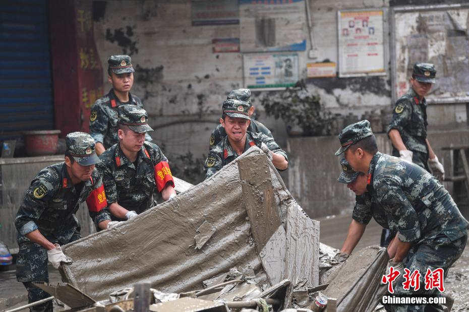 Oficiais e soldados limpam lama depois da inundação em Chongqing