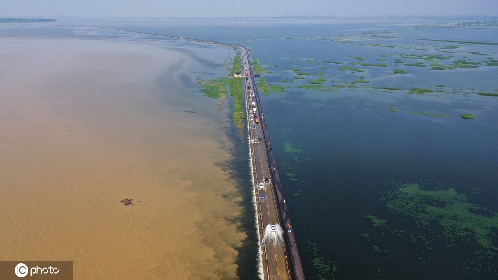 Veículos atravessam estrada inundada