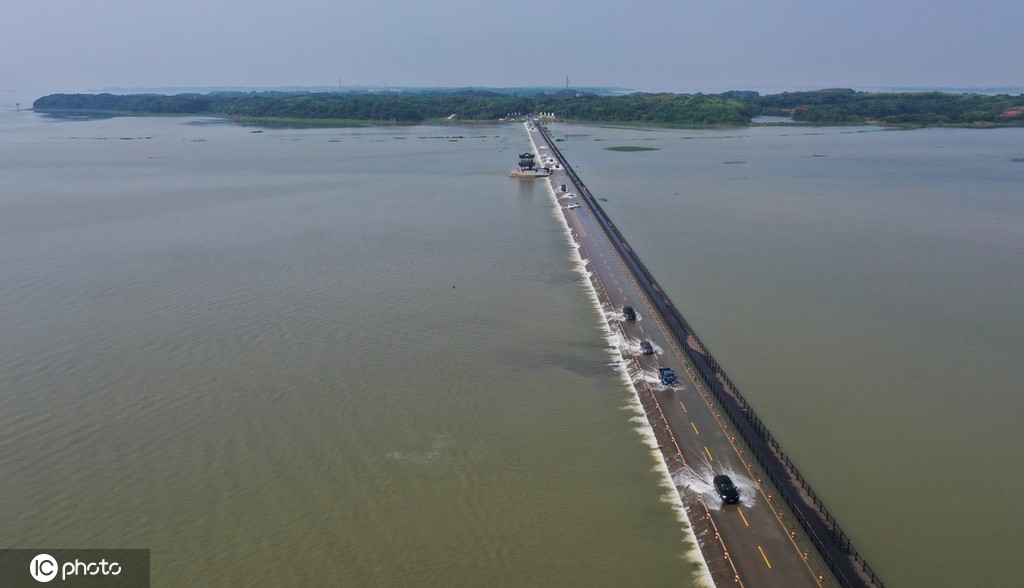 Veículos atravessam estrada inundada