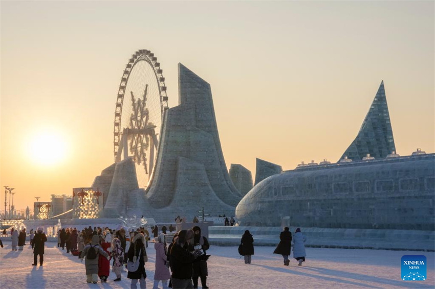 Turistas se divertem ao pôr do sol no Mundo de Gelo e Neve de Harbin, no nordeste da China