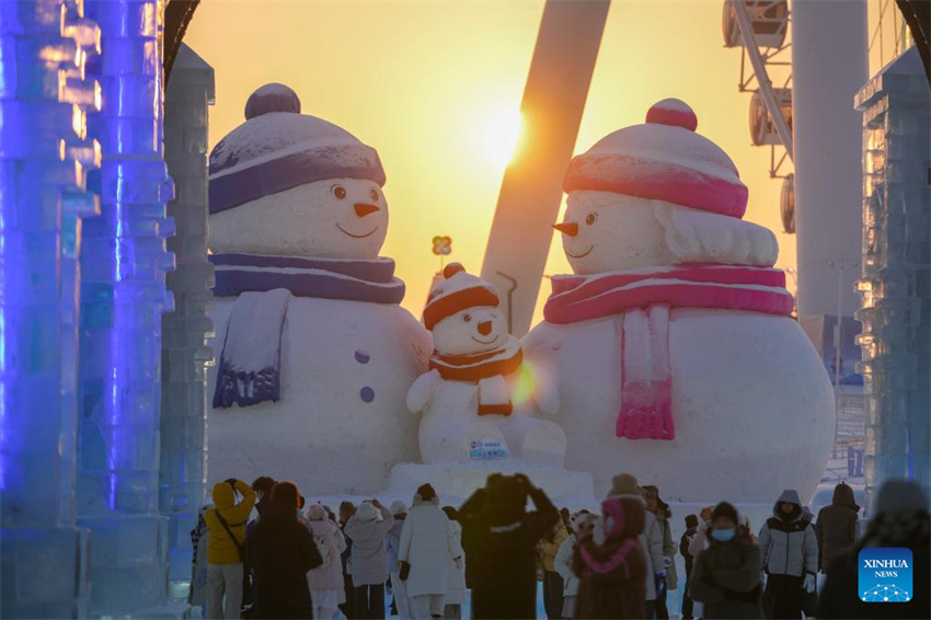 Turistas se divertem ao pôr do sol no Mundo de Gelo e Neve de Harbin, no nordeste da China
