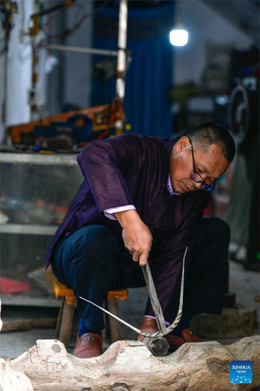 Um ourives trabalha em um ornamento de prata no município de Shuikou, condado de Liping, província de Guizhou, sudoeste da China, em 21 de abril de 2026.