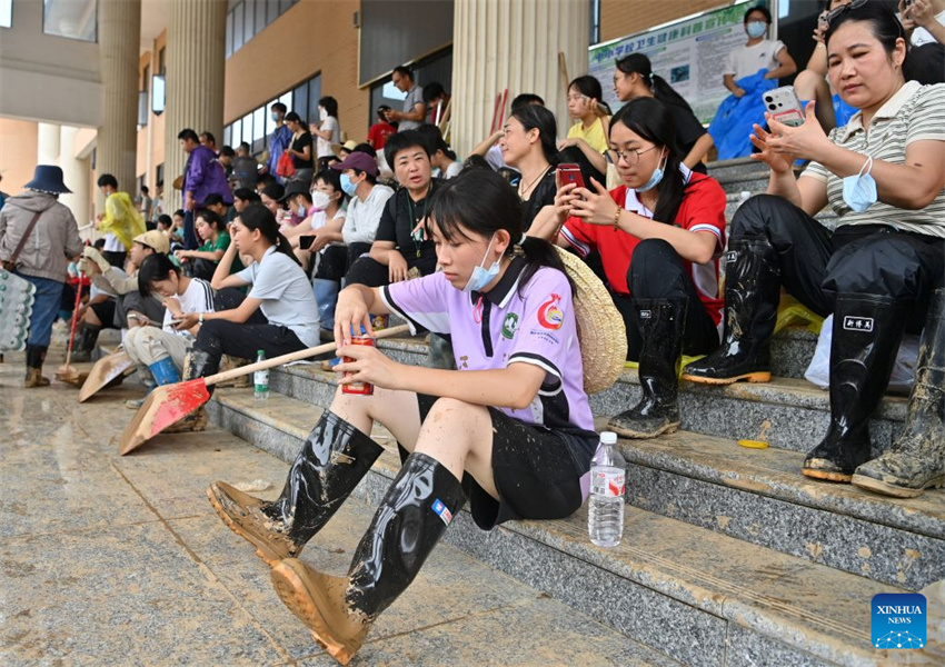 Pessoas fazem uma pausa durante os trabalhos de limpeza numa escola de ensino básico na cidade de Guigang, na Região Autônoma da Etnia Zhuang de Guangxi, no sul da China, em 15 de julho de 2026.