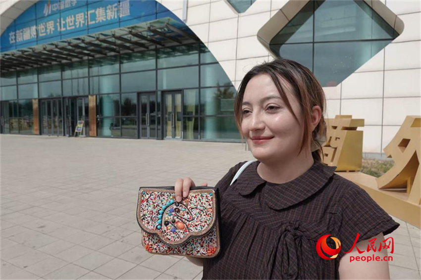 Muyim Aziz exibe mercadoria adquirida no Centro de Exposições e Comércio Alfandegado de Urumqi. (Foto: Wang Yuheng/Diário do Povo Online)